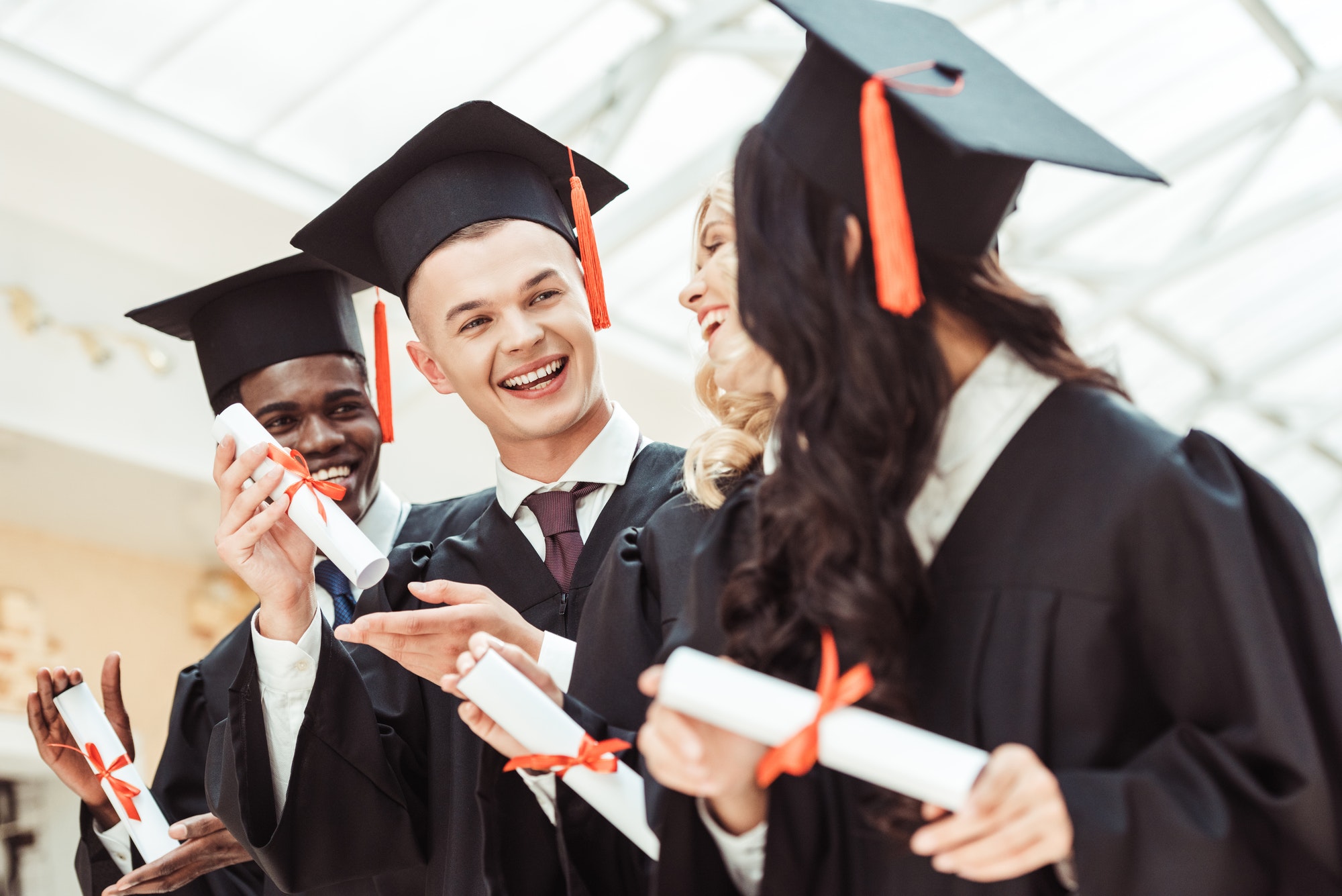 laughing graduated multiethnic students with diplomas